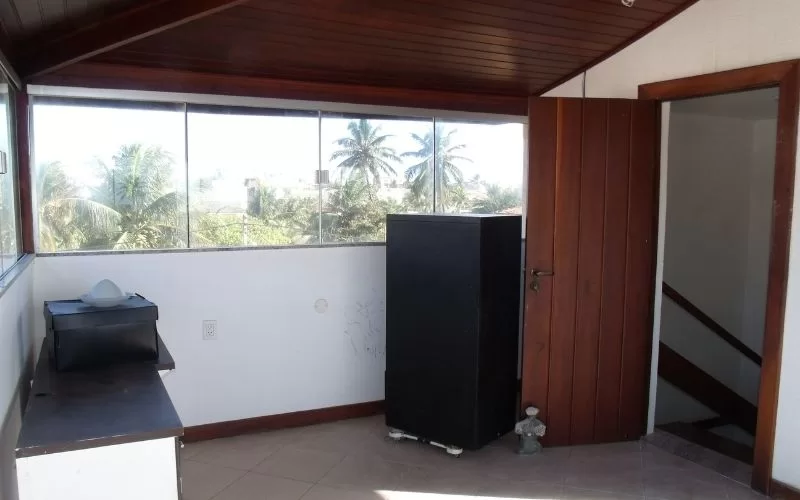 Varanda com mesa e árvores ao fundo.