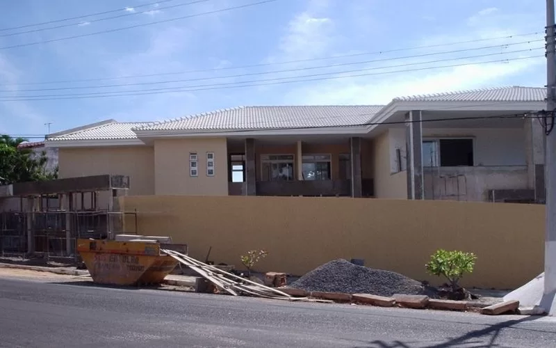 Casa em construção com contentor de entulho.