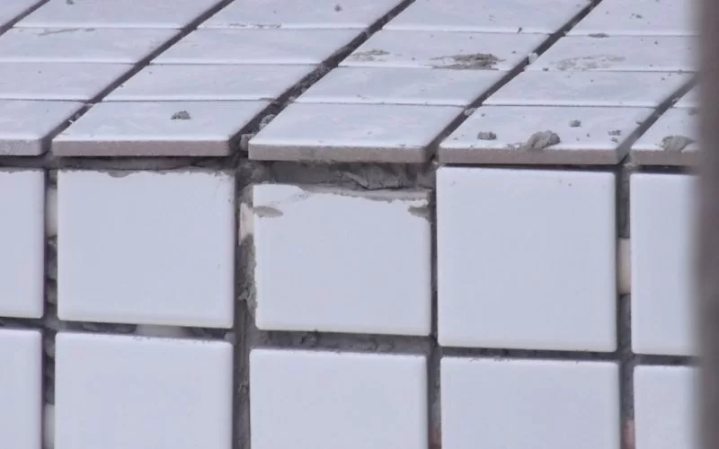 Falta de azulejo em parede parcialmente danificada.