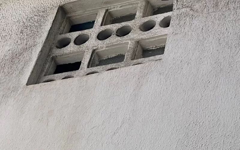 Janela de tijolos vazados em parede de concreto.