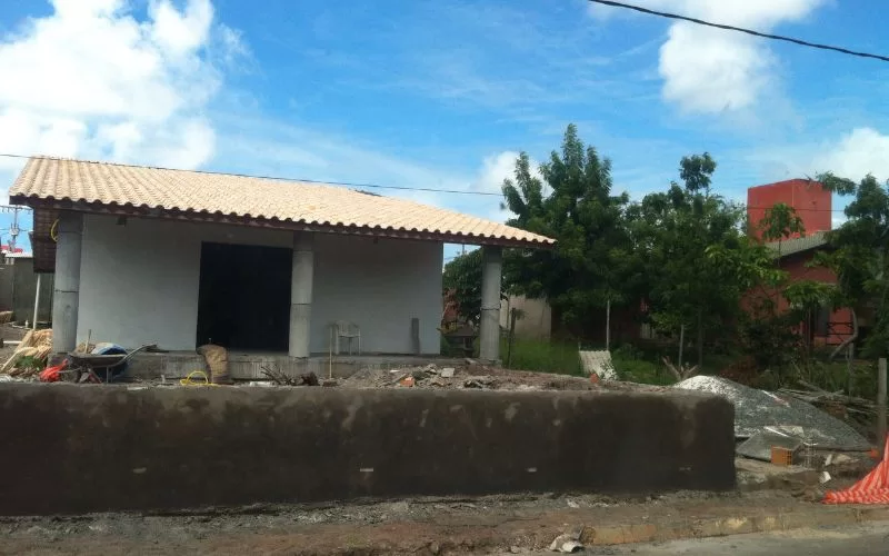 Casa em construção com jardim ao fundo.