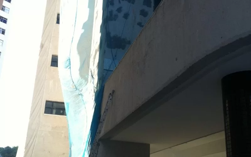 Fachada de prédio em construção com cobertura plástica.