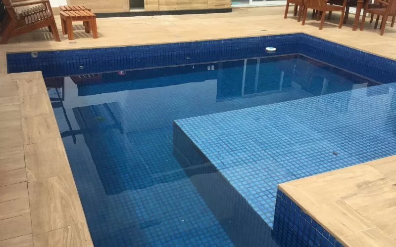 Piscina de azulejos azuis em terraço ensolarado.