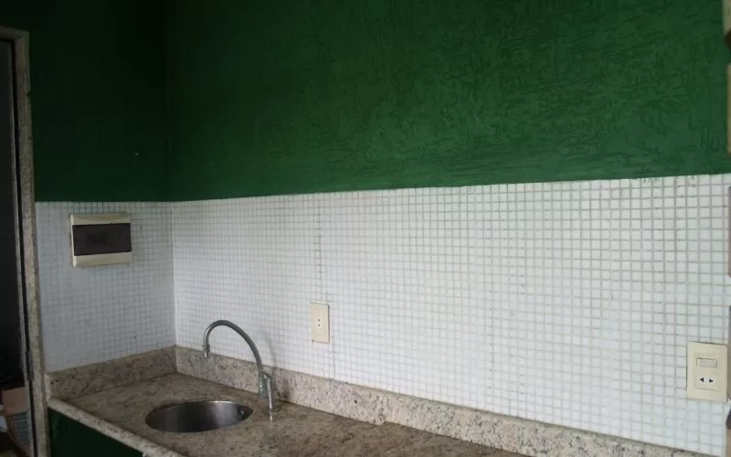 Cozinha com parede verde e azulejos brancos.