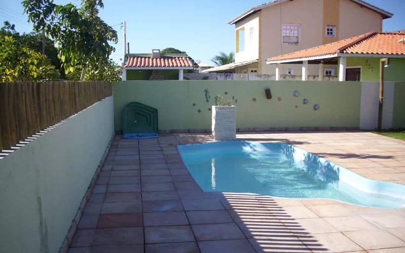 Piscina pequena em quintal com muro verde.