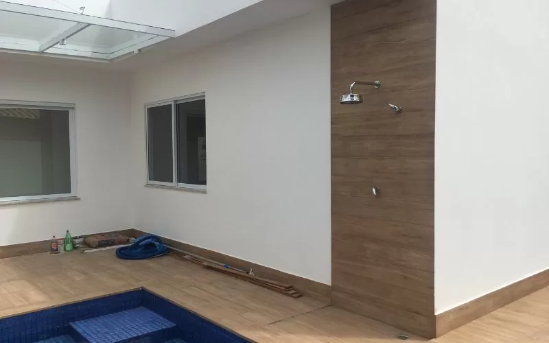 Área externa com chuveiro e piscina azul.