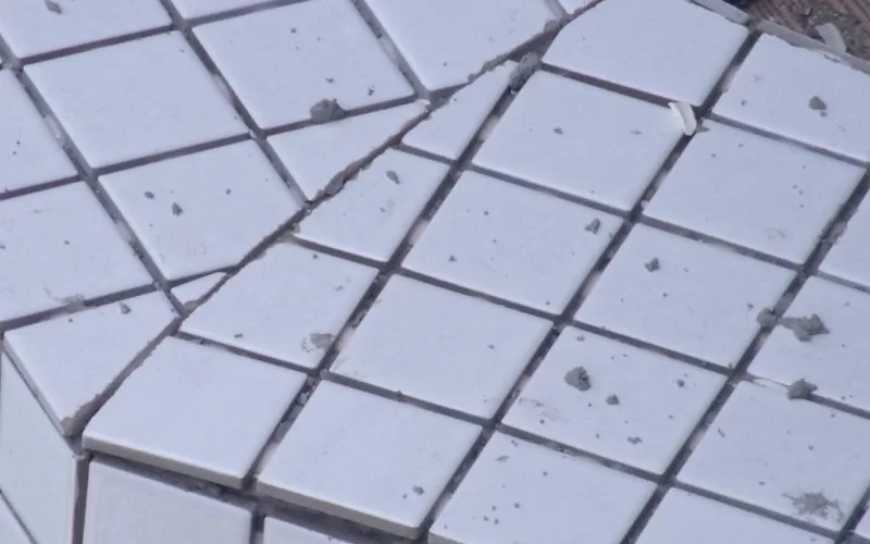 Azulejos brancos danificados e quebrados em chão.