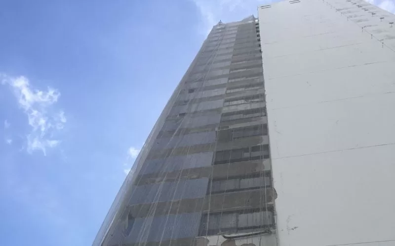 Prédio alto em reforma contra céu azul.