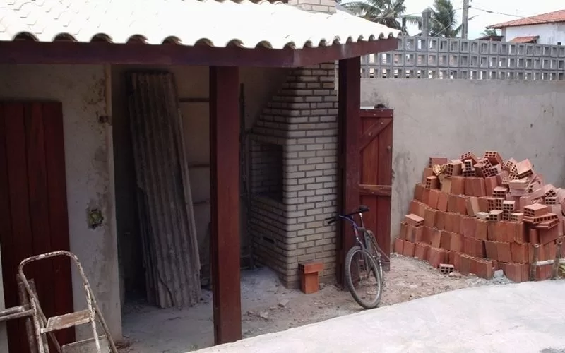 Pilha de tijolos ao lado de churrasqueira e bicicleta.