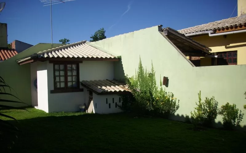 Quintal com casa pequena e relvado verde.
