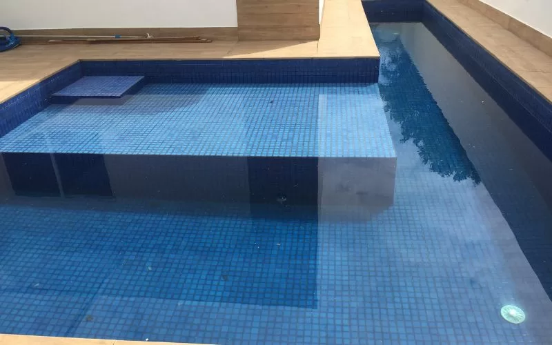 Piscina com revestimento azul e bordas de madeira.