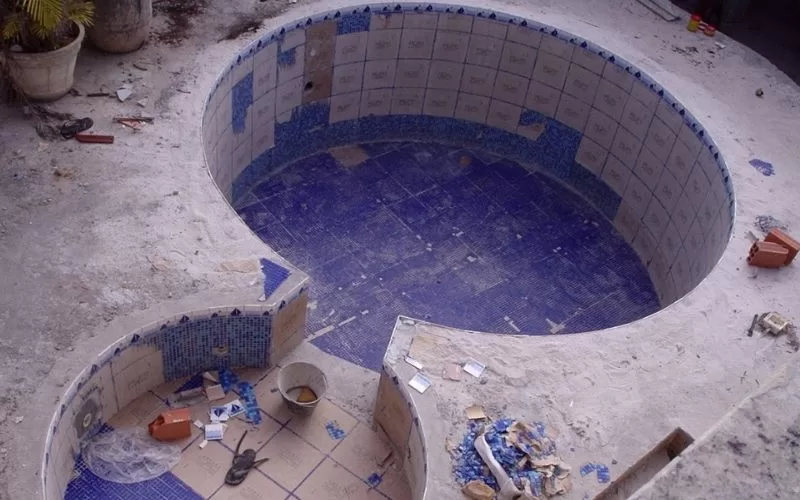 Piscina em construção com azulejos azuis.