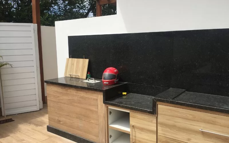 Bancada preta com armários e capacete vermelho.