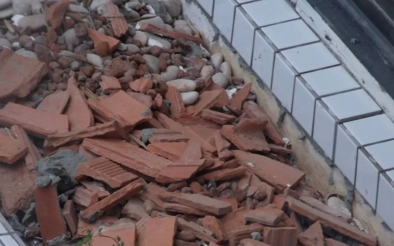 Cacos de tijolos vermelhos junto a azulejos brancos danificados.