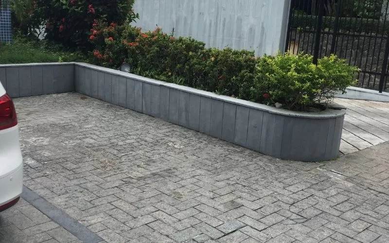 Estacionamento com canteiro de arbustos verdejantes.