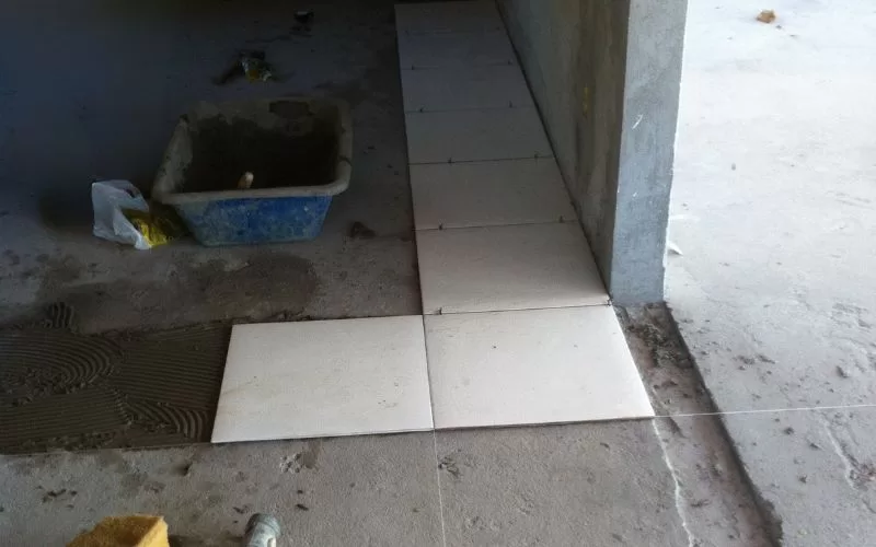 Colocação de azulejos no chão de cimento.