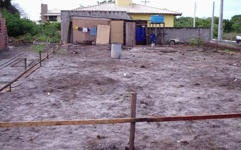 Terreno vazio com casa ao fundo e roupas secando.