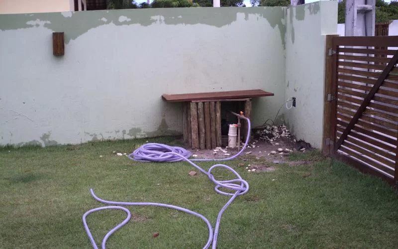 Jardim com mangueira e bancada de madeira.