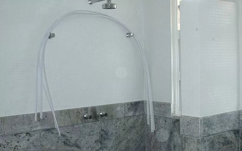 Casa de banho com chuveiro e paredes em azulejo.