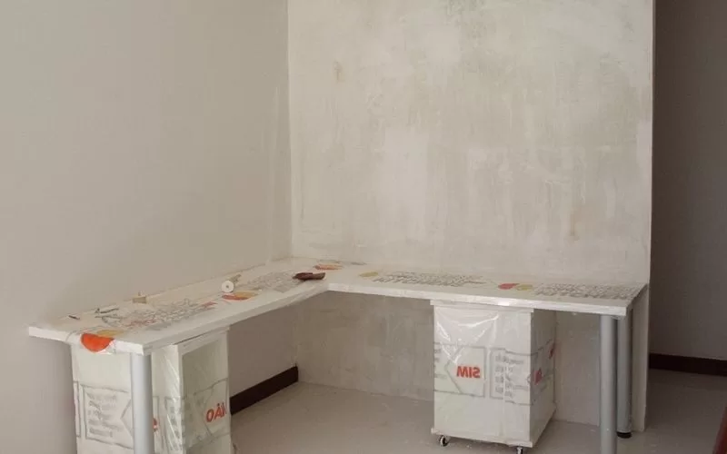 Esquina de sala com mesa parcialmente montada.