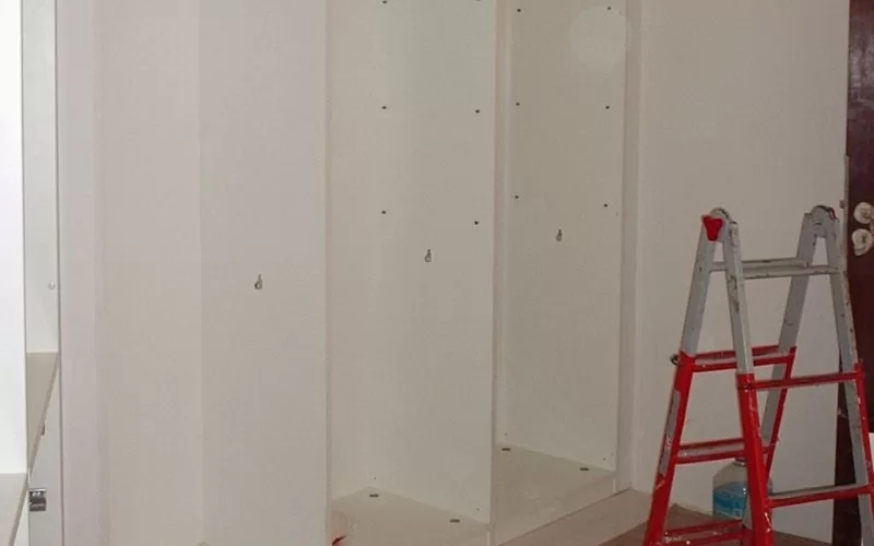 Armário embutido em construção com escada vermelha.