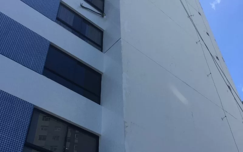 Prédio alto com janelas escuras e céu azul.