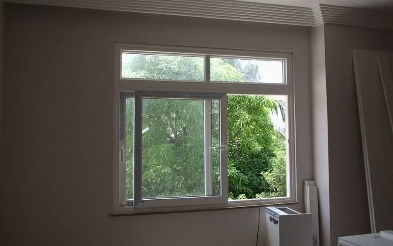 Janela aberta com vista para árvores verdes.