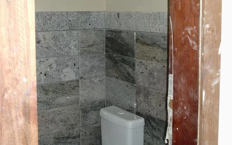 Casa de banho com azulejos cinzentos nas paredes.