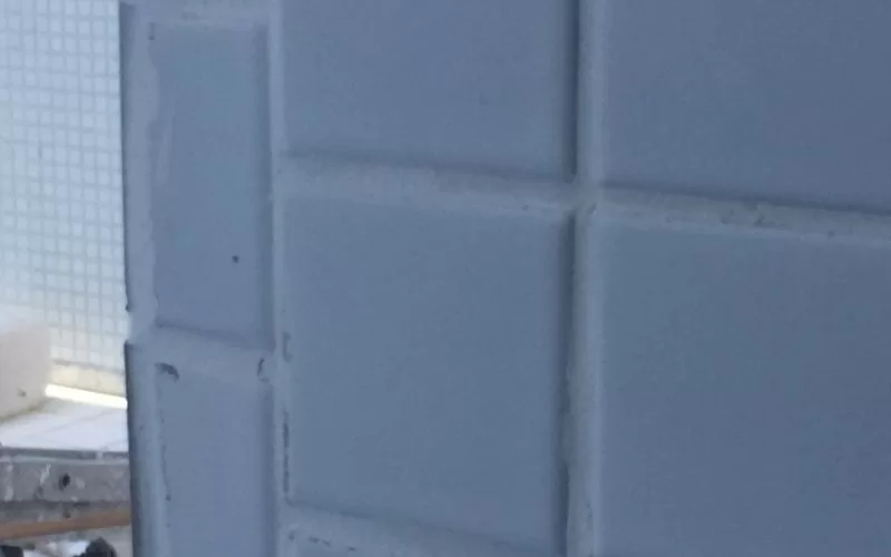 Parede de azulejos brancos em detalhe.