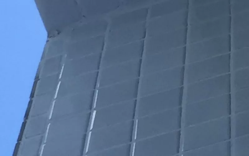 Parede de azulejos cinzas com teto azul.