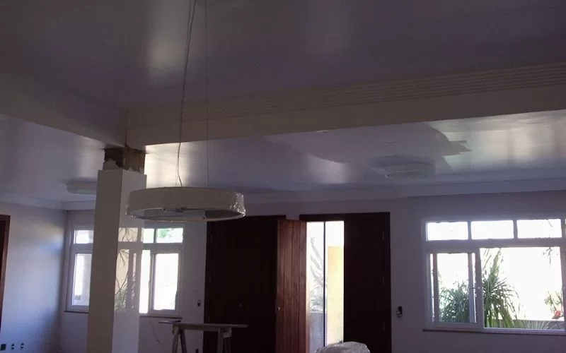 Sala com teto branco e luminária pendente.
