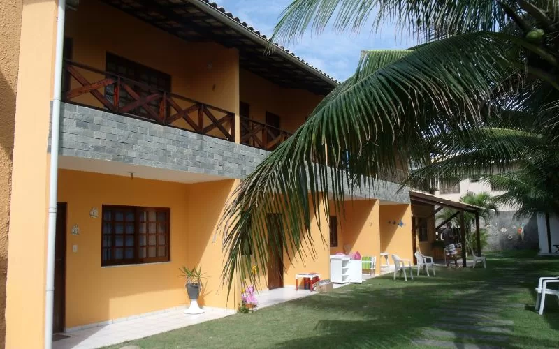 Casa amarela com varanda em jardim tropical