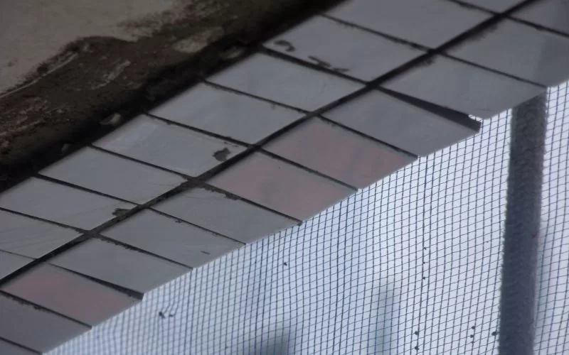 Telhas danificadas e tela de proteção em edifício.