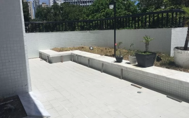 Terraço em azulejo branco com vasos de plantas.