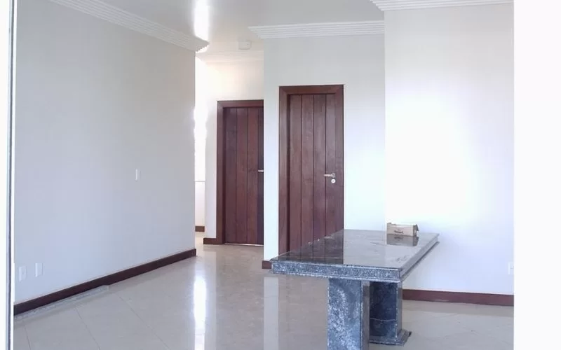 Sala com mesa de mármore e duas portas.