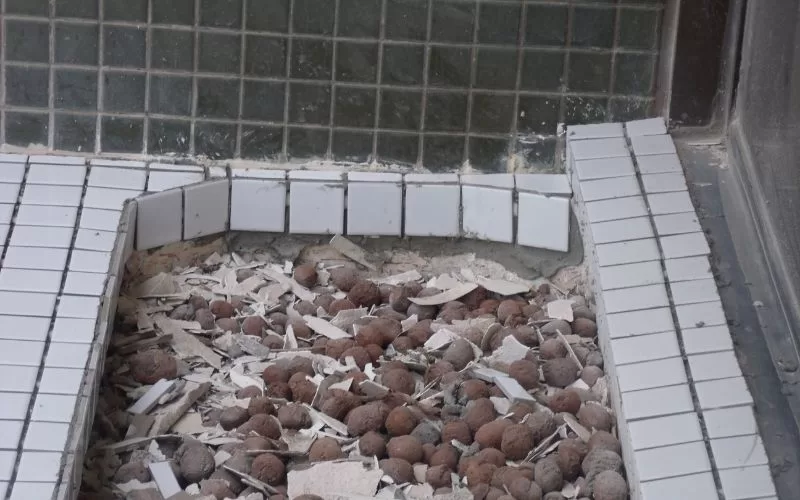 Piscina vazia com azulejos e entulho visíveis