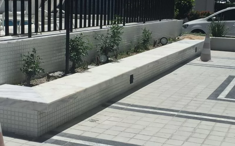 Jardim moderno com iluminação e pavimento claro.