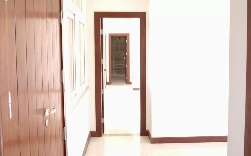 Corredor iluminado com portas em madeira marron escura.