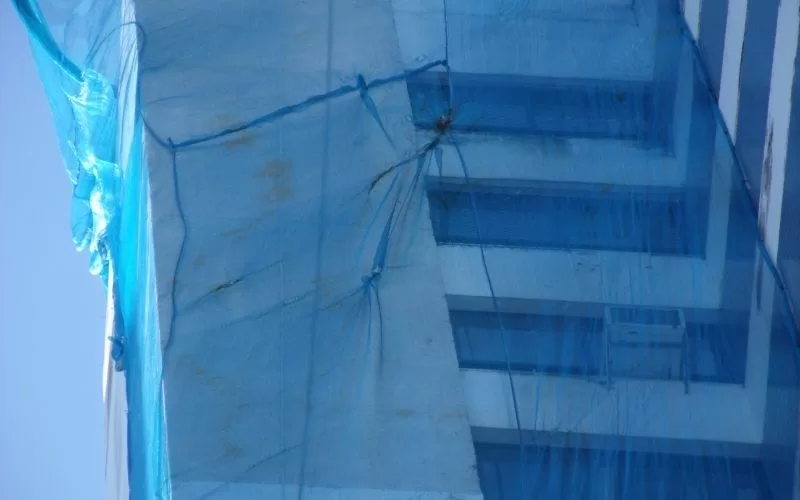 Edifício coberto por rede azul de proteção