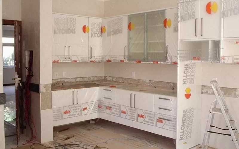 Cozinha moderna em remodelação, móveis brancos.