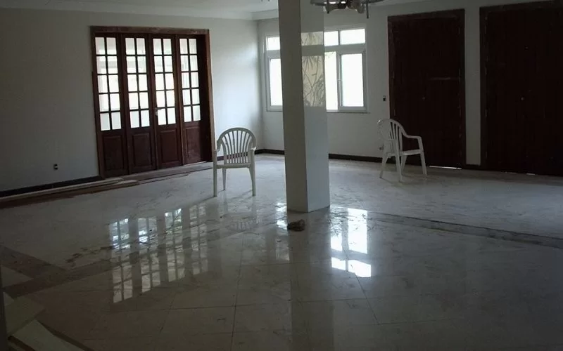 Sala ampla vazia com cadeiras e janelas grandes.