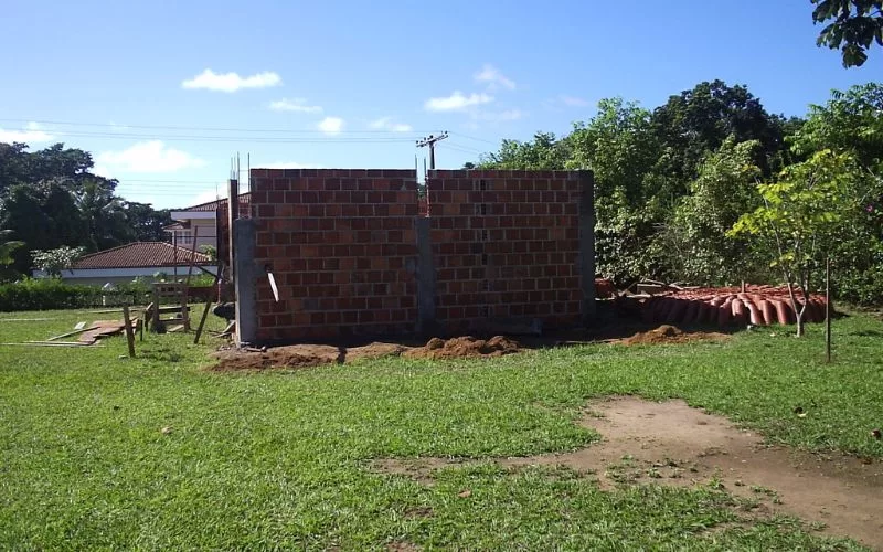 Estrutura de tijolos em construção num jardim verde.