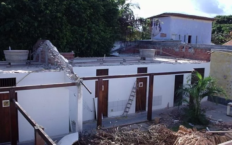 Construção com telhado removido e escada na parede.