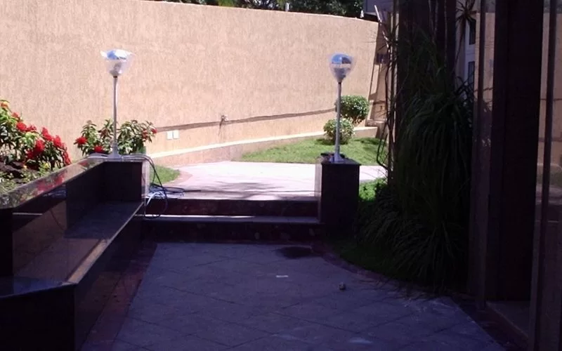 Jardim com caminho pavimentado e lâmpadas externas.