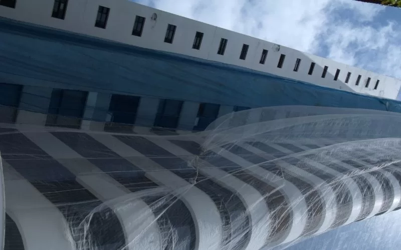 Edifício coberto por lona sob céu azul.
