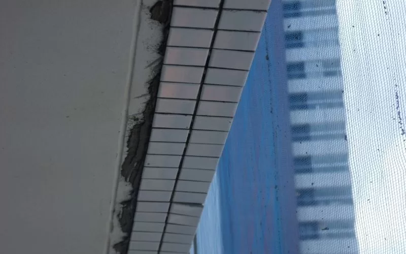 Detalhe de azulejos e tela azul em edifício.