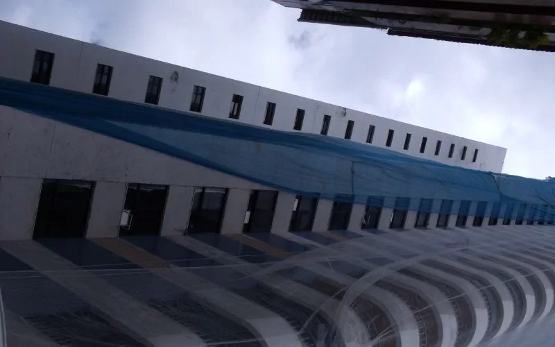 Prédio em construção com andaimes azuis.
