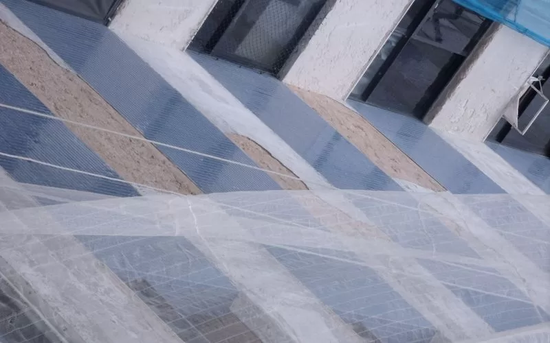 Fachada de edifício com andaimes cobertos por rede.