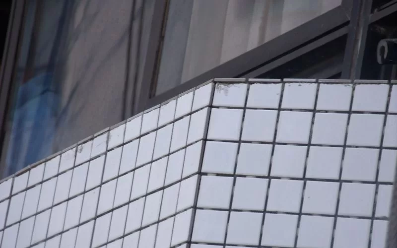 Detalhe de fachada com azulejos brancos quadrados.