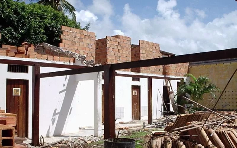 Construção inacabada com paredes de tijolo expostas.